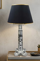 Rustic wooden bedside table lamp with black fabric lampshade and gold detailing placed on a black table in minimalist interior setup
